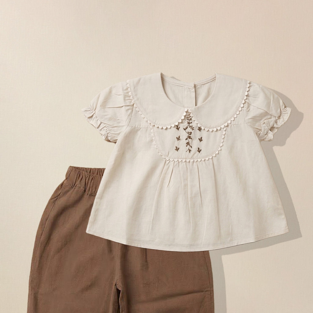 Close-up of floral embroidery detail on girls' Peter Pan collar top