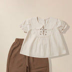 Close-up of floral embroidery detail on girls' Peter Pan collar top