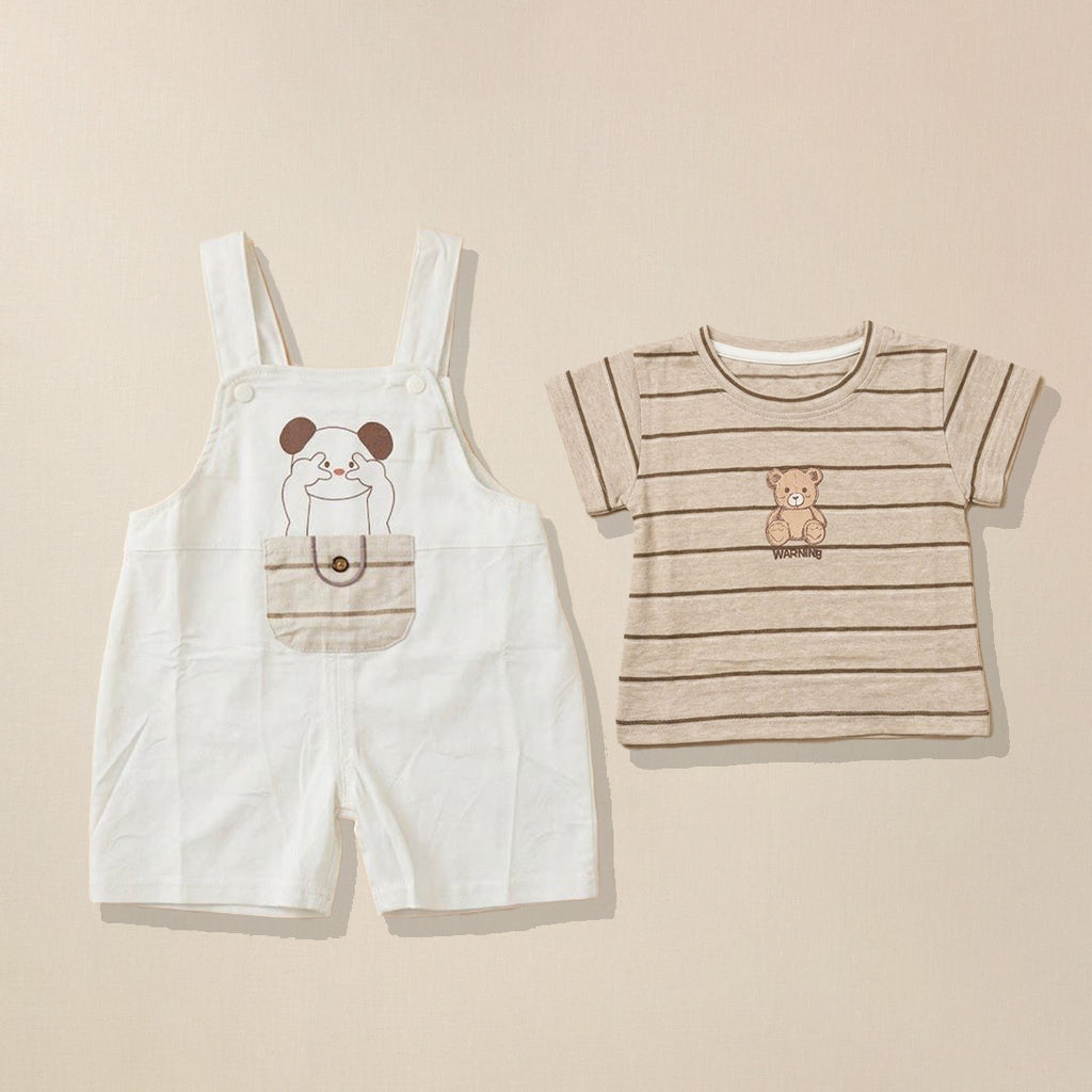 Children's clothing set with white overalls and brown striped bear t-shirt on a beige background. 