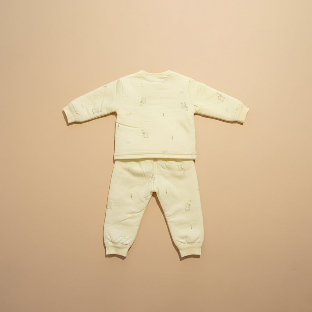 Light yellow baby outfit with long-sleeve top and pants on a beige background