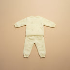 Light yellow baby outfit with long-sleeve top and pants on a beige background