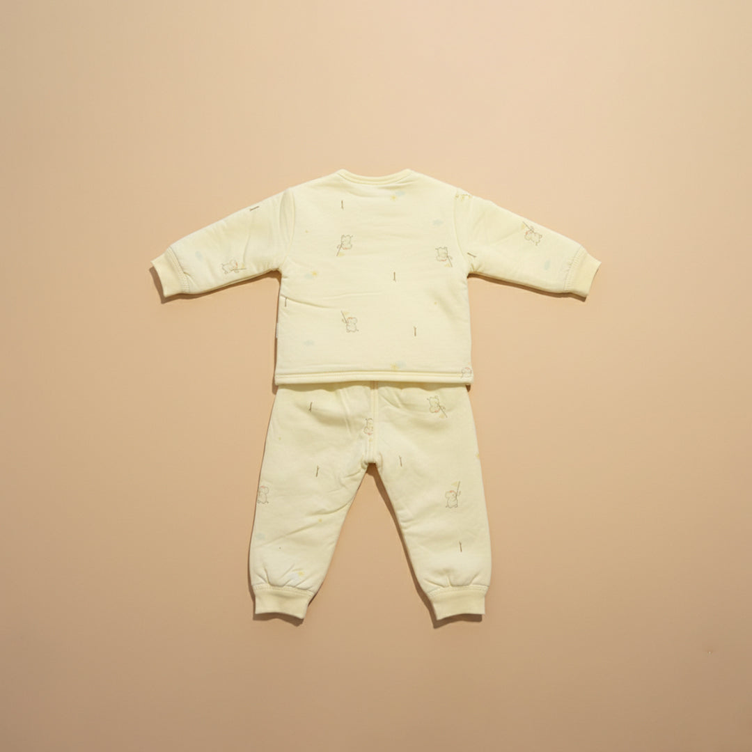 Light yellow baby outfit with long-sleeve top and pants on a beige background